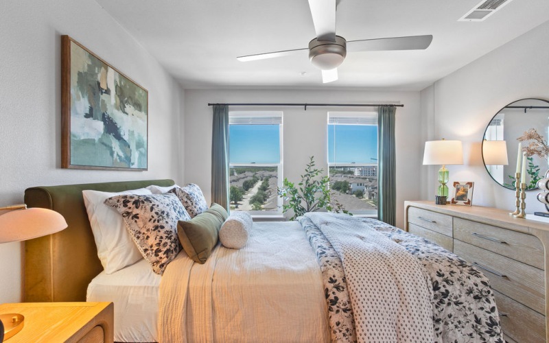 A bedroom with a bed and a fan at Residences at Rubi apartments in Austin, Texas.